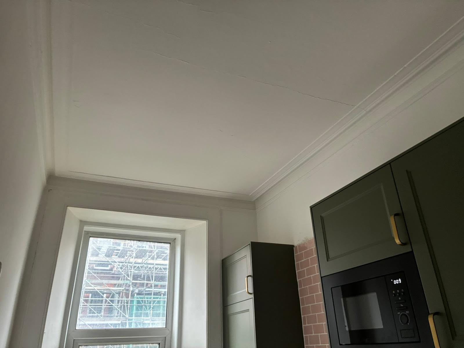 Kitchen with painted green cupboards, white walls and a freshly painted ceiling