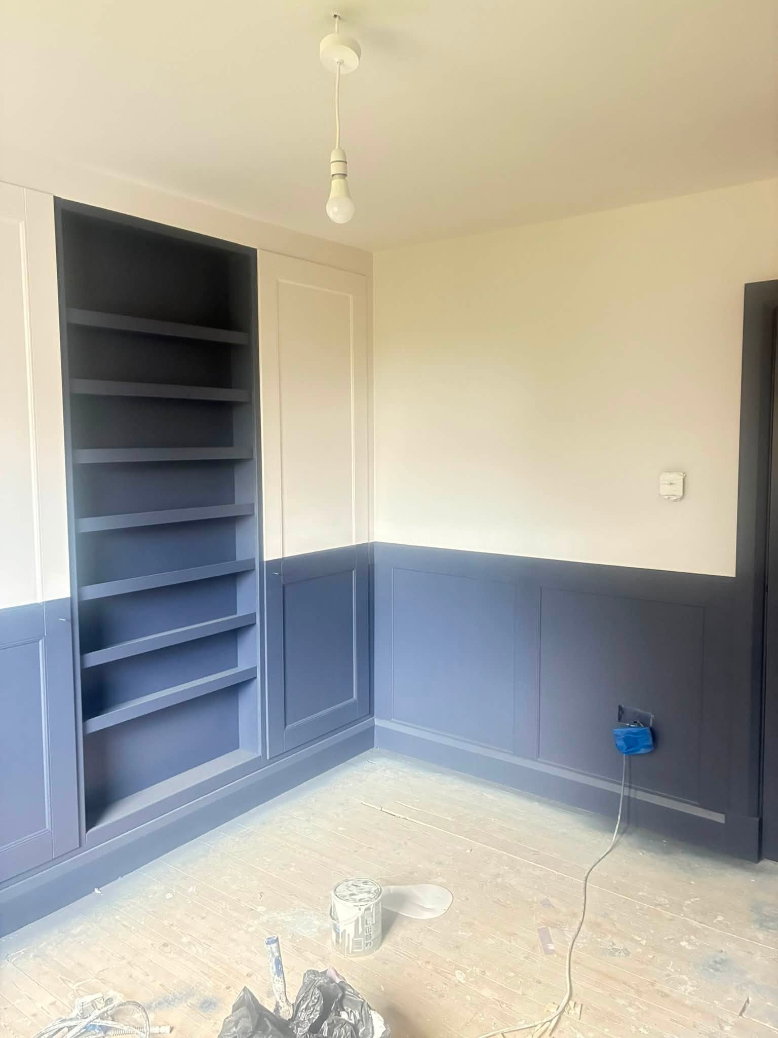 Spray-finished navy fitted shelves and wall panelling