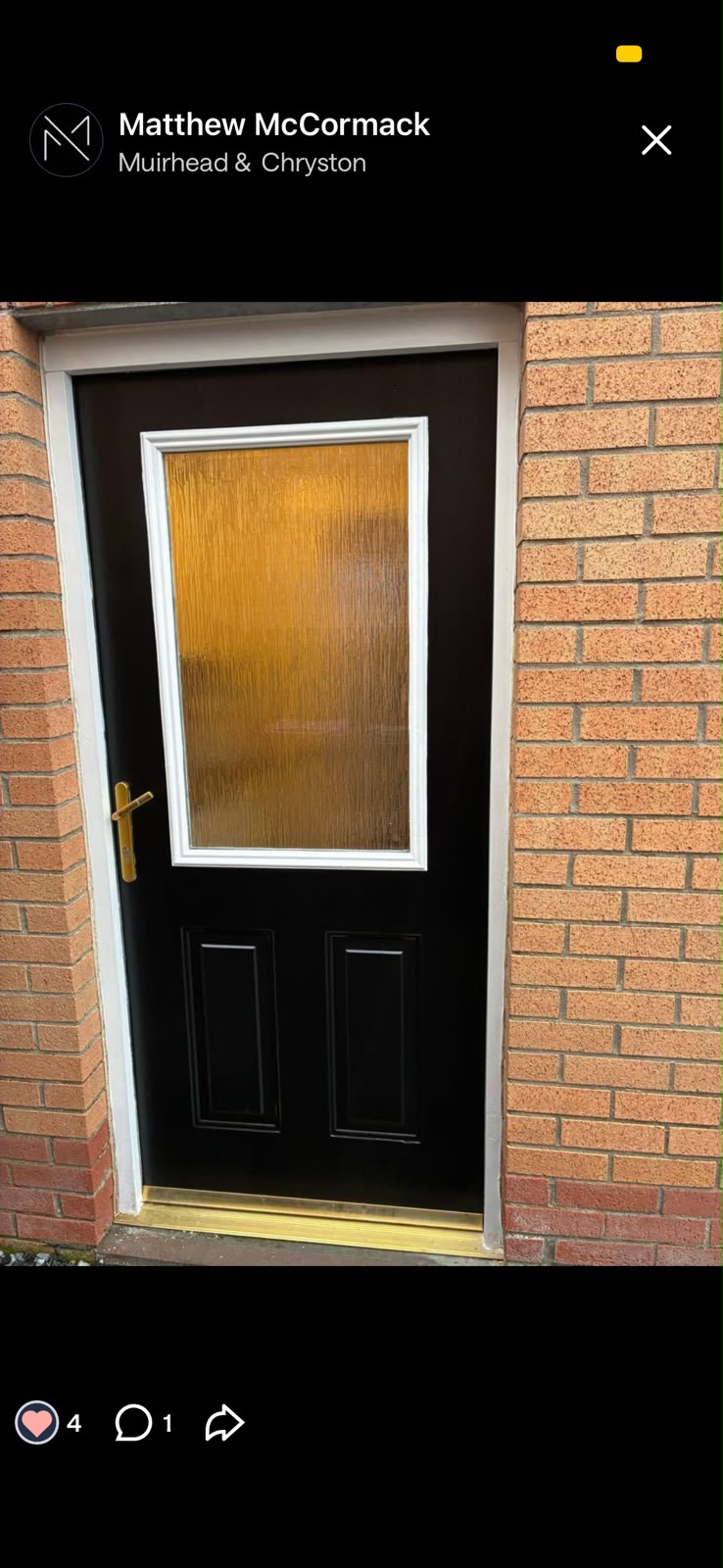Black painted front door with a white frame set in a brick wall