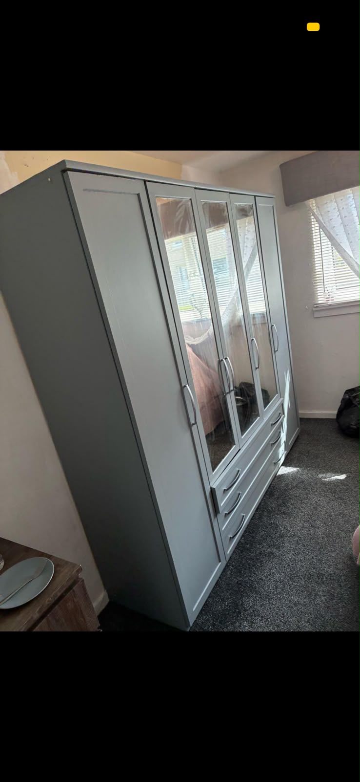 Grey painted wardrobe in a bedroom with finished walls