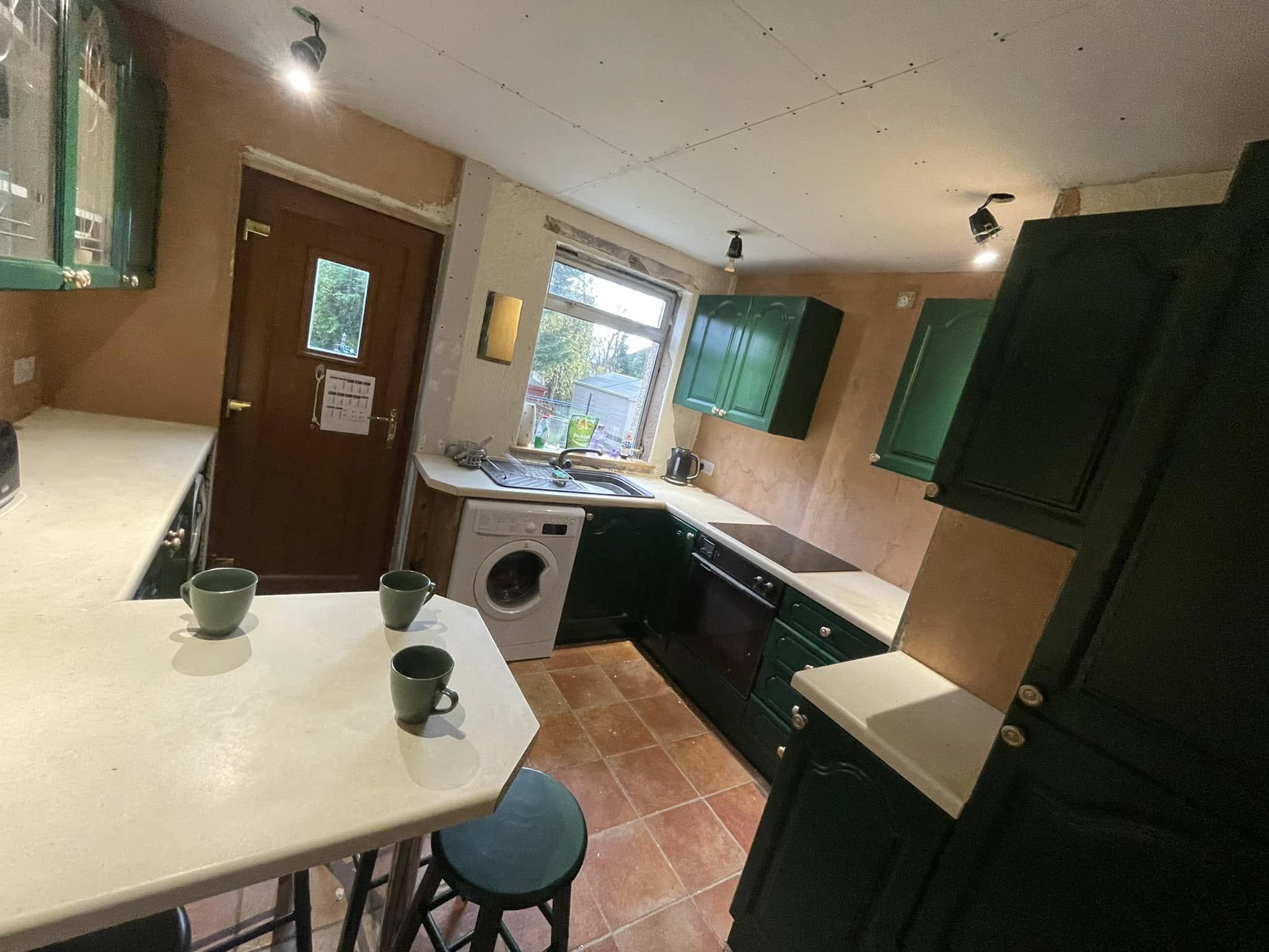 Kitchen cupboard painting in a galley kitchen with dark green units